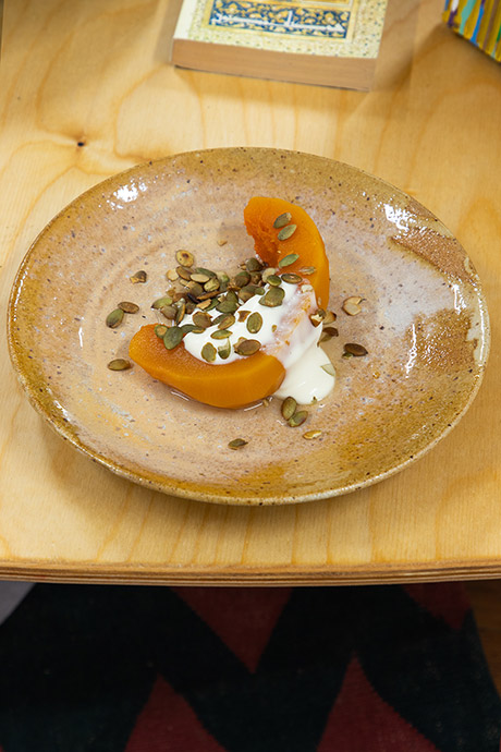 candied pumpkin dish with clotted cream and pumplin seeds centrally plated on a speckled and casually glazed handmade ceramic tableware