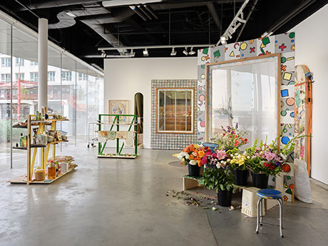 Installation view with flowers stands in the forground