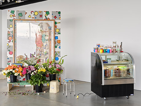 Installation view with window facade of a flowers shop, 3 steps showing about 10 buckets full of flowers