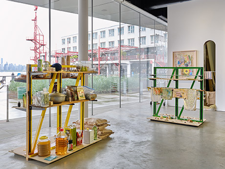 Installation view with shelf sculptures resembling grocery store shelves in foreground