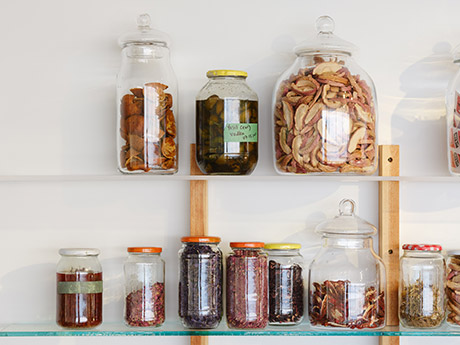 glass jars with dried fruit, herbs and flowers, liquid bitters inside them