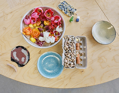 fresh flowers inside a metal bowl on top of the table, egg carton with marbles inside and a bright turqoise plate