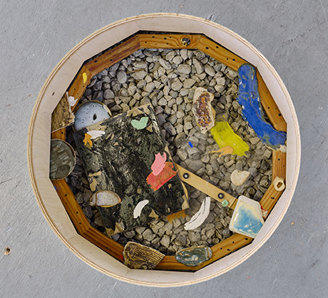 sculpture cut out on the ground, wooden frame 12 sided hexagon adorned with colourful ceramic blobs and paintings on plexiglas  and flowers and plaster.