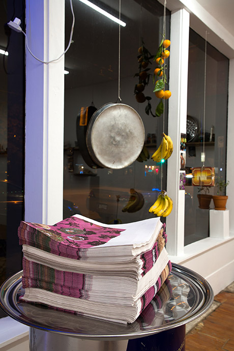 stack of newsprint posters by the artists sitting on tray, sitting on redbull stand